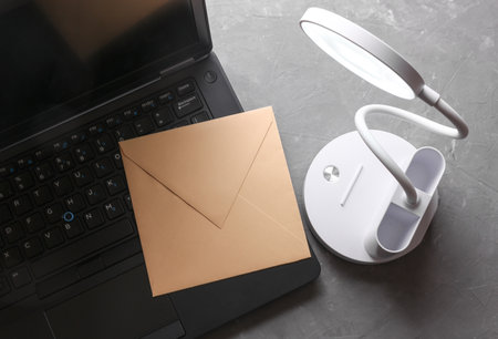 Desk LED lamp illuminates laptop keyboard with envelopeの写真素材
