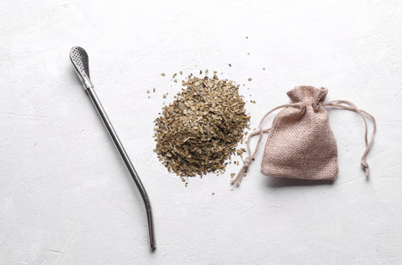 Dry yerba mate in a miniature burlap bag and bombilla on a white concrete backgroundの写真素材