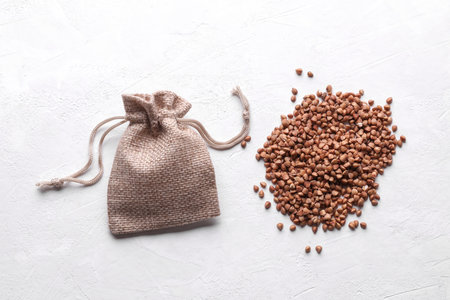 Buckwheat grains in a miniature burlap bag on a white concrete backgroundの写真素材