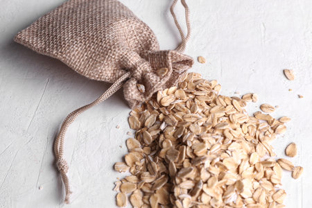 Dry oatmeal in a miniature burlap bag on a white concrete backgroundの写真素材