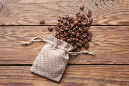 Coffee beans with miniature burlap bags on wooden tableの写真素材