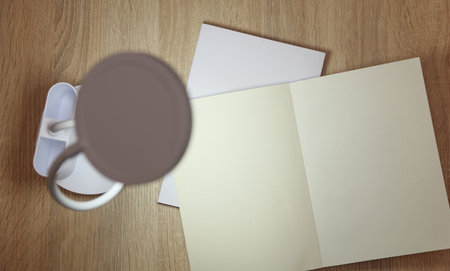 Modern LED lamp illuminates open blank notebook on table. Mockup for designの写真素材