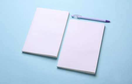 Magazines, sketchbooks or notebooks with white blank covers on blue background. Mockup for designの写真素材