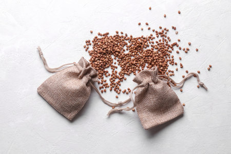 Buckwheat grains in a miniature burlap bags on a white concrete backgroundの写真素材