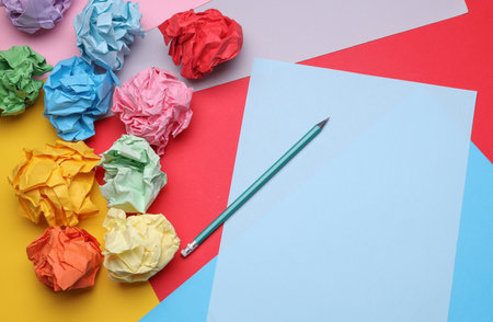 Colored balls of crumpled paper and paper sheet with pencil. Lack of ideas, stress, depression, business conceptの写真素材