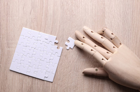 Robotic wooden hand of puppet assembles puzzle on table.の写真素材