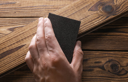Man's hand sanding wooden boards with a sanding blockの写真素材