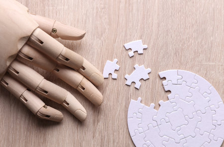 Robotic wooden hand assembles puzzle on table. Artificial intelligence training concept