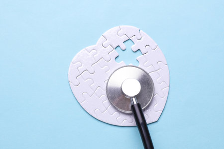 Stethoscope and white puzzle in the shape of a heart. Diagnosis and treatment of heart diseases. Mockup for designの写真素材