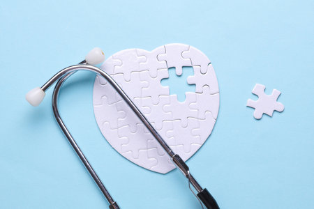 Stethoscope and white puzzle in the shape of a heart. Diagnosis and treatment of heart diseases. Mockup for designの写真素材