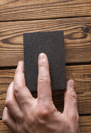 Man's hand sanding wooden boards with a sanding blockの写真素材