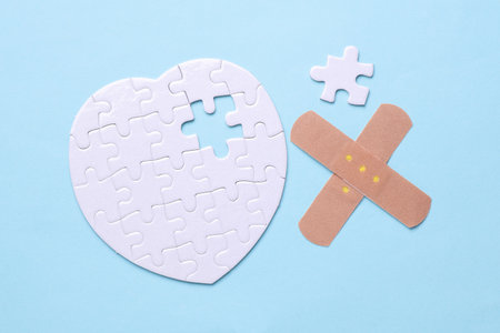 Medical plaster and white puzzle in the shape of a heart. Diagnosis and treatment of heart diseases.