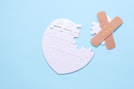 Medical plaster and white puzzle in the shape of a heart. Diagnosis and treatment of heart diseases.の写真素材