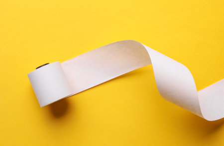 Cash register empty white tape roll on yellow backgroundの写真素材