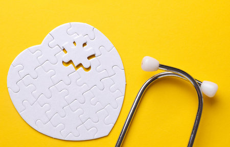 Stethoscope and white puzzle in the shape of a heart. Diagnosis and treatment of heart diseases. Mockup for designの写真素材