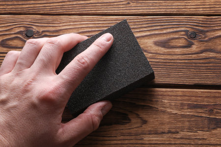 Man's hand sanding wooden boards with a sanding blockの写真素材