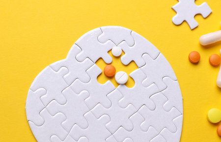 Pills and white puzzle in the shape of a heart. Diagnosis and treatment of heart diseases. Mockup for designの写真素材