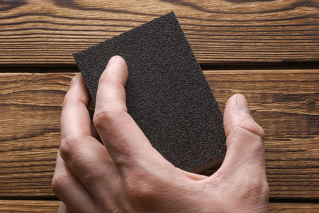 Man's hand sanding wooden boards with a sanding blockの写真素材