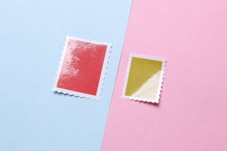 Blank Postal paper adhesive stamps on pink blue background. Marks for letterの写真素材