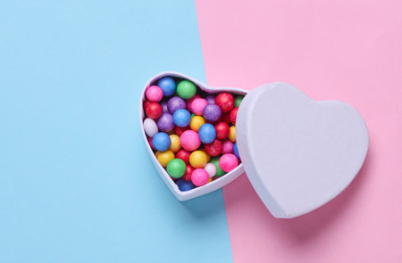 Heart shaped box filled with colorful balls on a blue and pink background