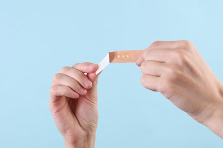 Hand holding medical plaster on blue background