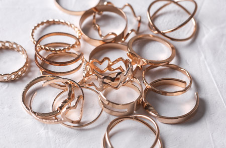 Many Gold rings of different shapes on a white concrete background. Jewelry store, beauty conceptの写真素材