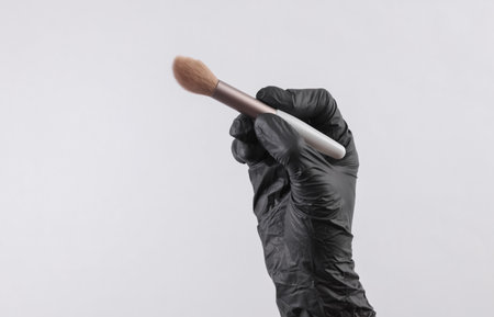Makeup artist's hand in black glove holding brushの写真素材