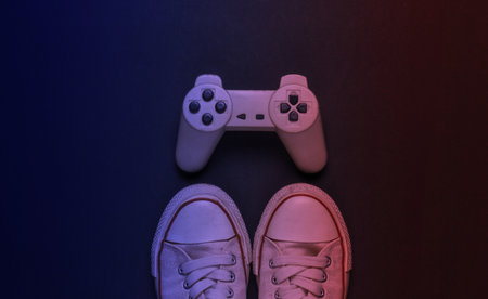 Retro old sneakers and gamepad in neon light. 80s. Top view