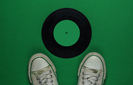 Retro old sneakers and vinyl record on green background. 80s. Top viewの写真素材