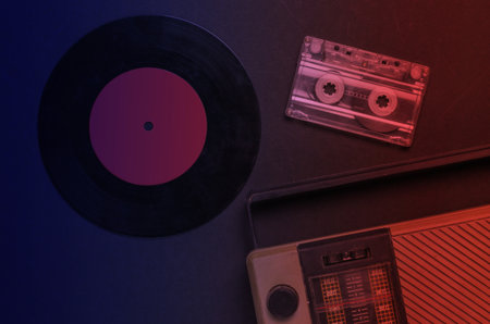 Retro media. Radio receiver, vinyl record, audio cassette in neon light. Top view.