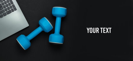 Fitness concept. Online training for a coaching profession. Laptop, dumbbell on black background. Top view. Copy spaceの写真素材