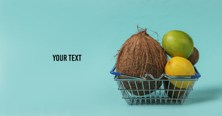 Shopping basket and tropical fruits on blue background. Shopping at the supermarket. Healthy food...