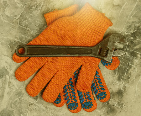 Work gloves and wrench on a gray concrete background. Top view