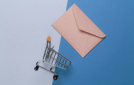 Pink envelope and shopping trolley on two tone background. Mockup for valentines day, wedding or birthday. Top viewの写真素材