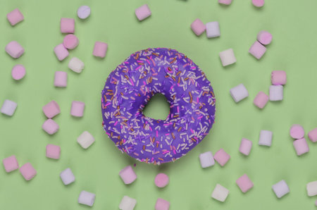 Minimalistic food still life. Glazed donut with marshmallows on green background. Vanilla color trend. Pop Artの写真素材