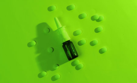 Medicine concept. Bottle with pills, nasal spray. Neon green night lightの写真素材