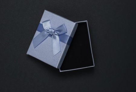 Open Gift box with bow on black background. Composition for christmas, birthday or wedding. Top view