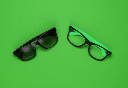 Stylish glasses without lenses and sunglasses on green background. Top viewの写真素材