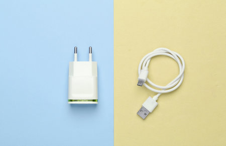 Charger with cable on yellow blue pastel background. Top view