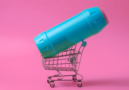 Shopping trolley with plastic bottle on pink background.の写真素材