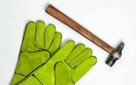 Green work gloves, hammer isolated on white background. Top view