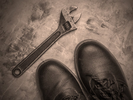 Leather work boots and wrench on concrete background. Top viewの写真素材