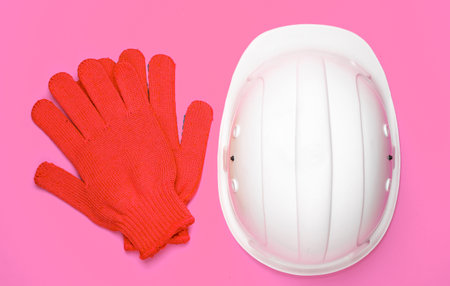 Safety equipment on pink background. Construction helmet, gloves. Top viewの写真素材