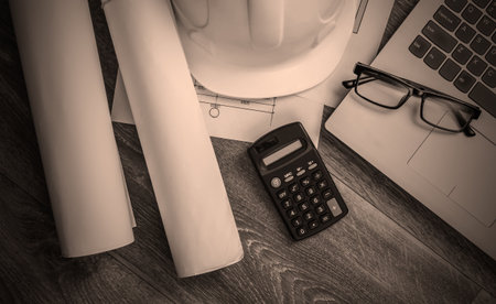 Creative layout of architects with roll drawings, architectural project plan, construction helmet on floor, workspace with laptop. Top view. Flat layの写真素材