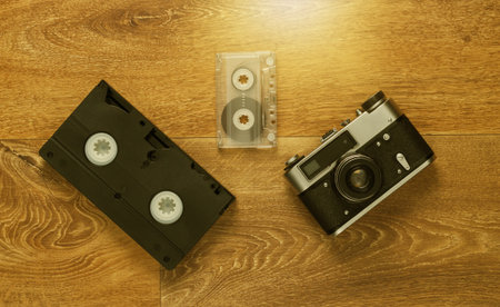 Video cassettes, audio cassette, old-fashioned film camera on the floor. Retro media 80s. Top viewの写真素材