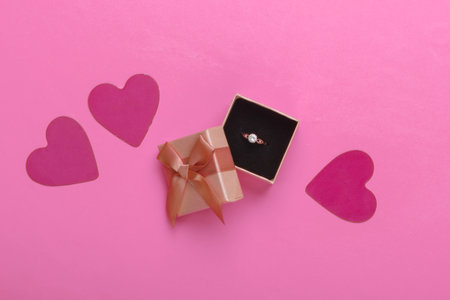 Romantic concept. Golden ring with diamond in box, hearts on pink background. Marriage proposal, gift for Valentine's Day. Top viewの写真素材