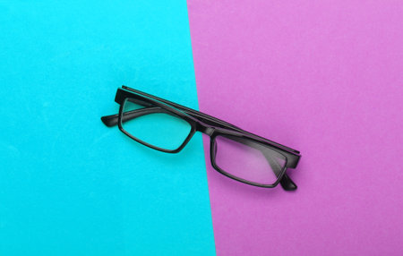 Classic eyeglasses on pink-blue background. Top view. Minimalismの写真素材