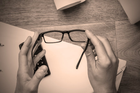Engineer workspace. Hands hold glasses on the background of the workplace. Top viewの写真素材