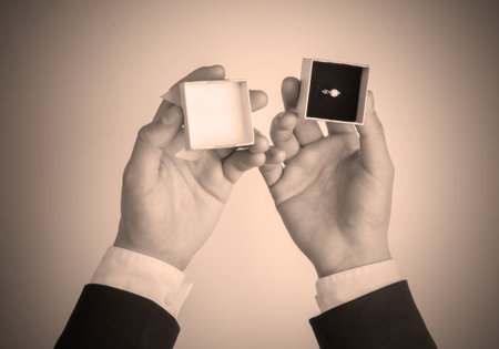 Marriage proposal. Man`s hands holding a gift box with a golden diamond ringの写真素材