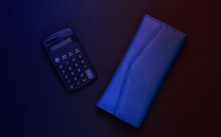 Calculator with leather wallet in neon light. Family budget, economical calculation, additional...